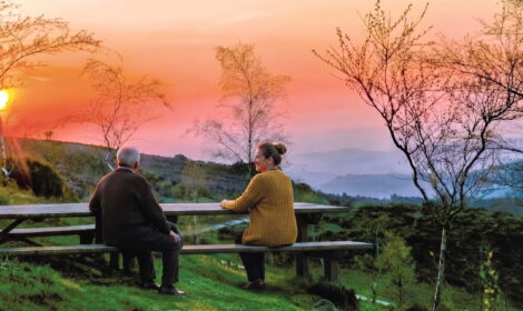 begleitete Seniorenreise Nordzentral-Portugal, Senior mit Begleitung auf einer Bank bei Sonnenuntergang